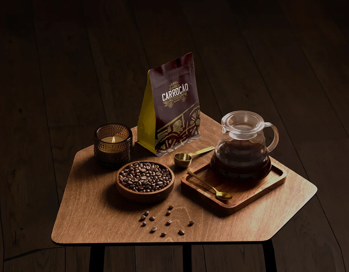 Embalagem da marca Café Carroção sobre mesa de madeira, ao lado de grãos de café torrados e coador de vidro